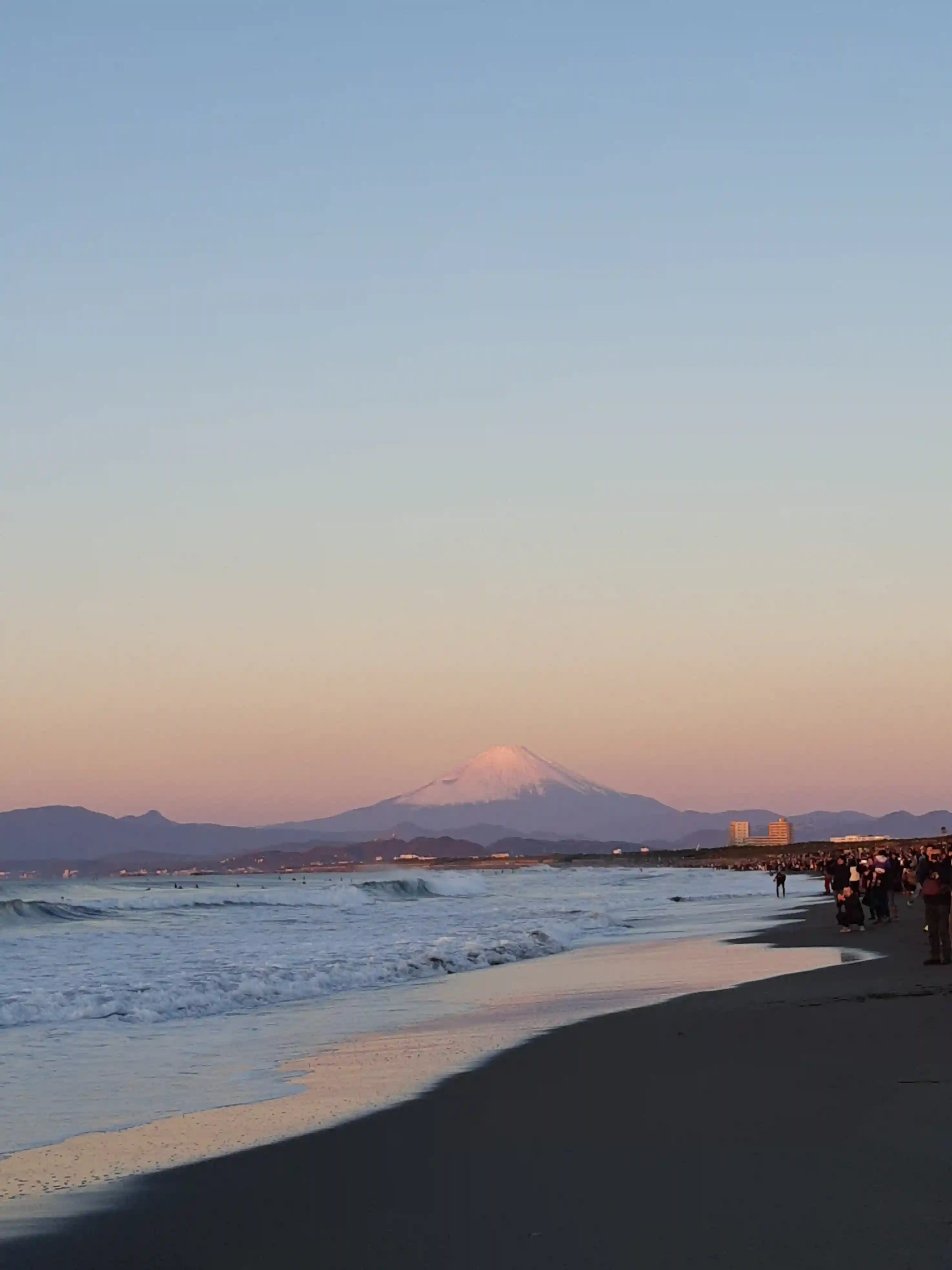 2024年の初日の出。長い砂浜が続いており、正面に赤く染まった富士山がある画像。