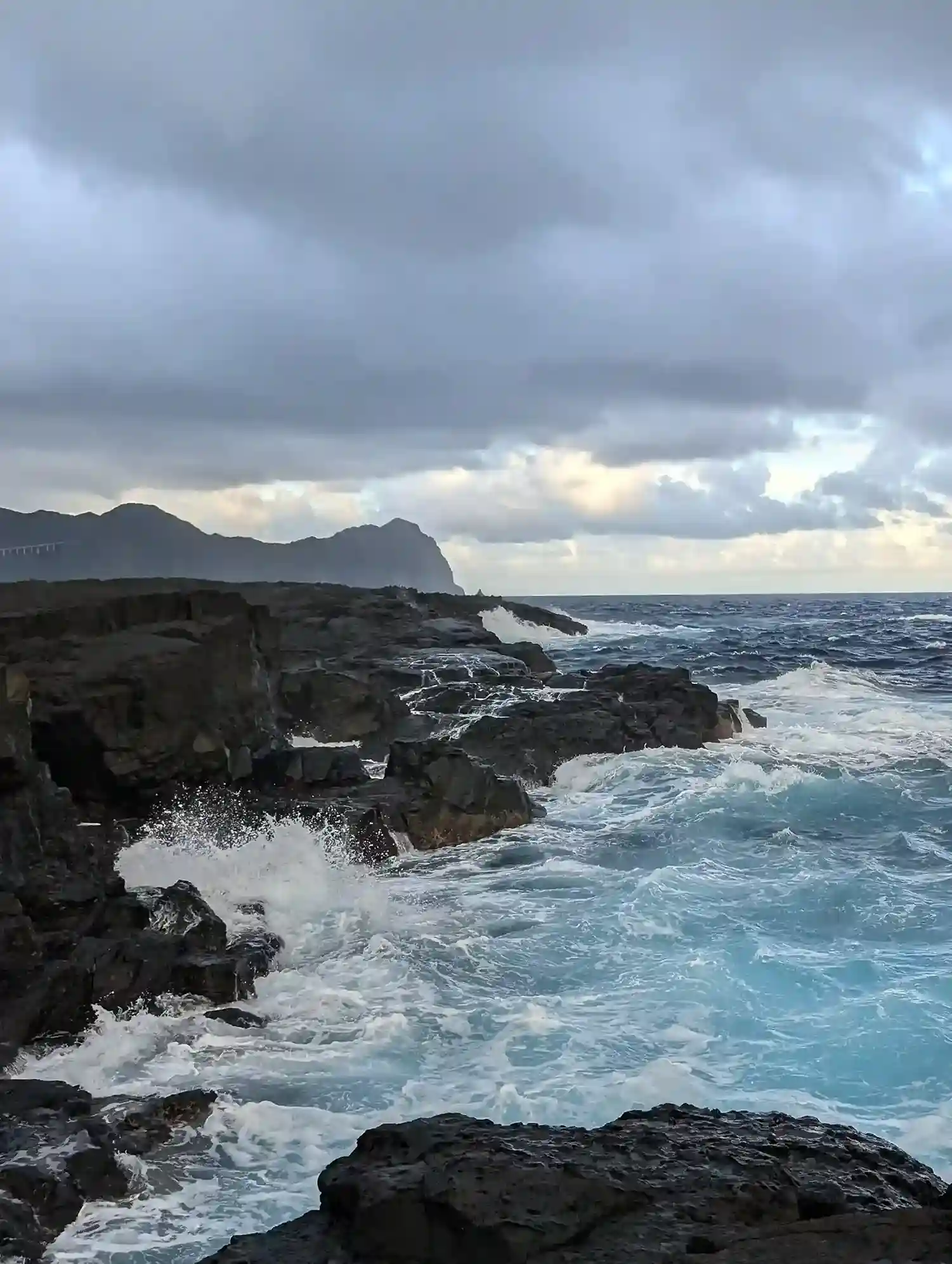 八丈島の海岸。波が岩にぶつかって水しぶきをあげている画像。